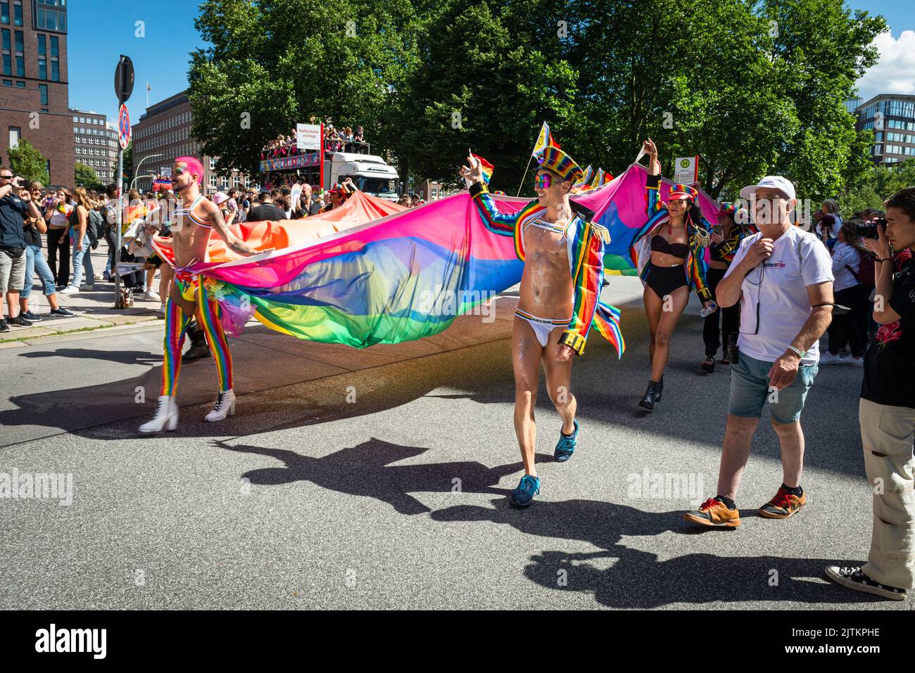 Colourful, fanciful and sparsely dressed participants of the Christopher Street Day CSD Parade in Hamburg carry a rainbow flag, Germany Stock Photo