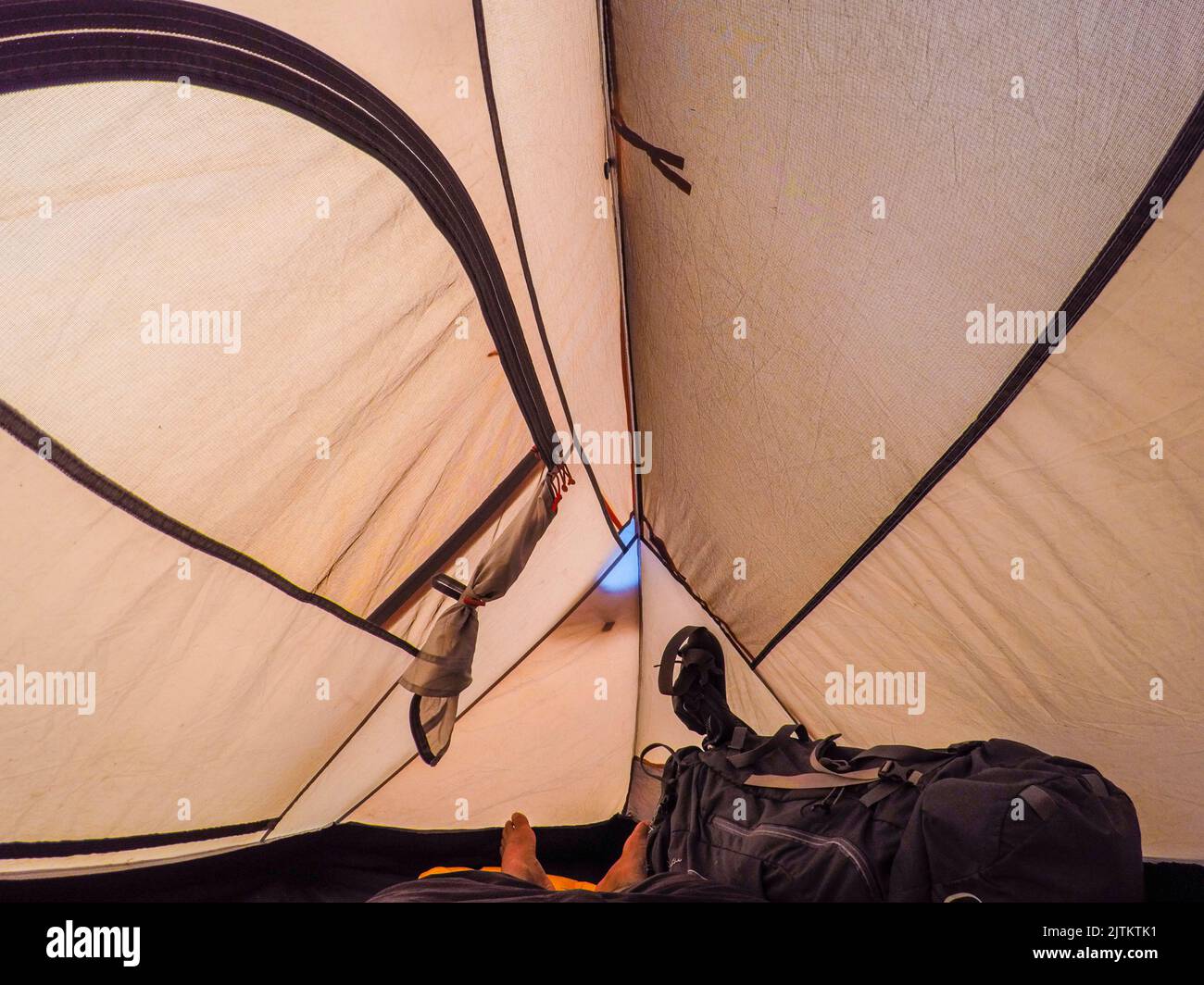 man lying inside a closed camping tent. Stock Photo