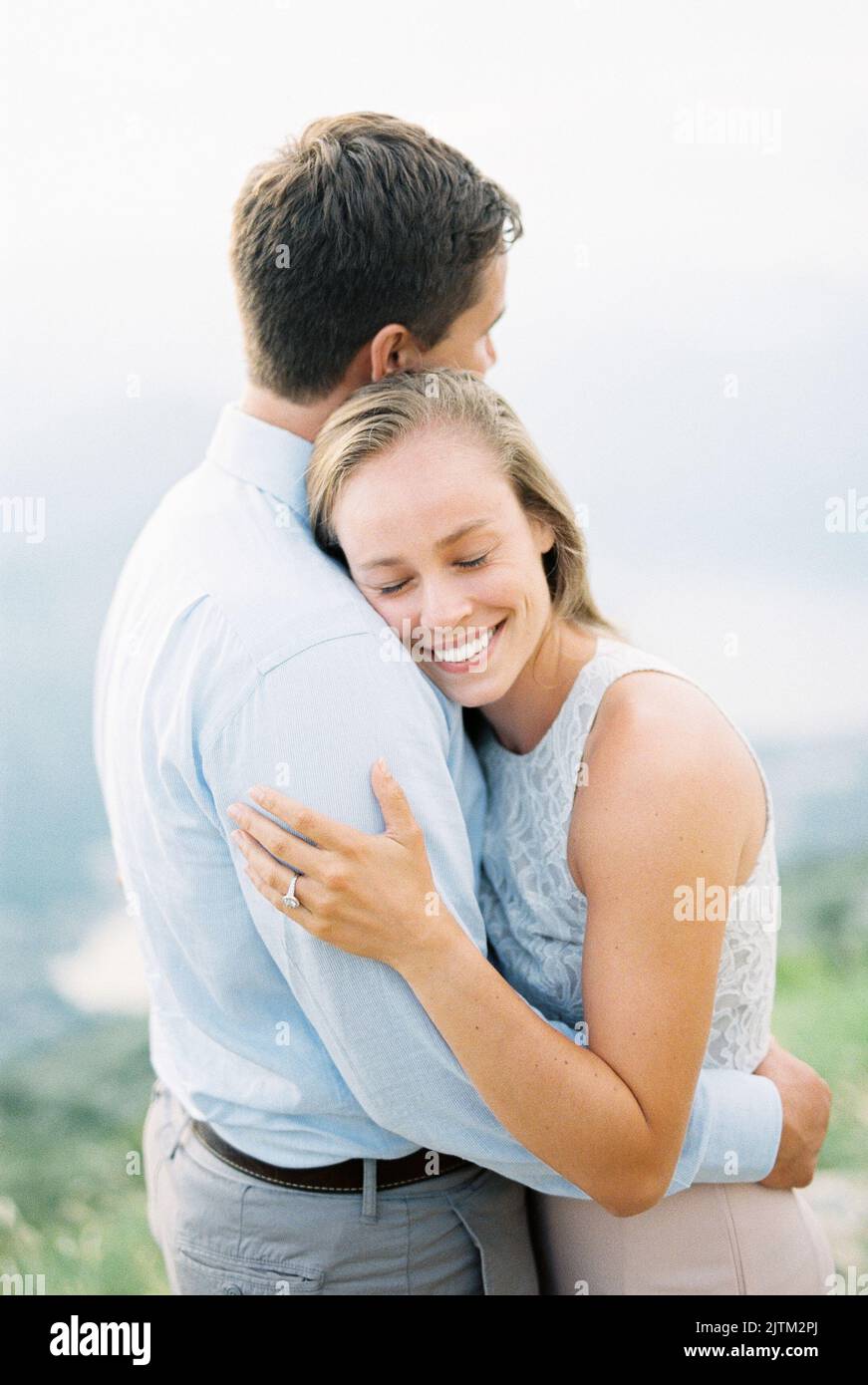 Smiling woman hugging a man while standing on a mountain. Portrait ...
