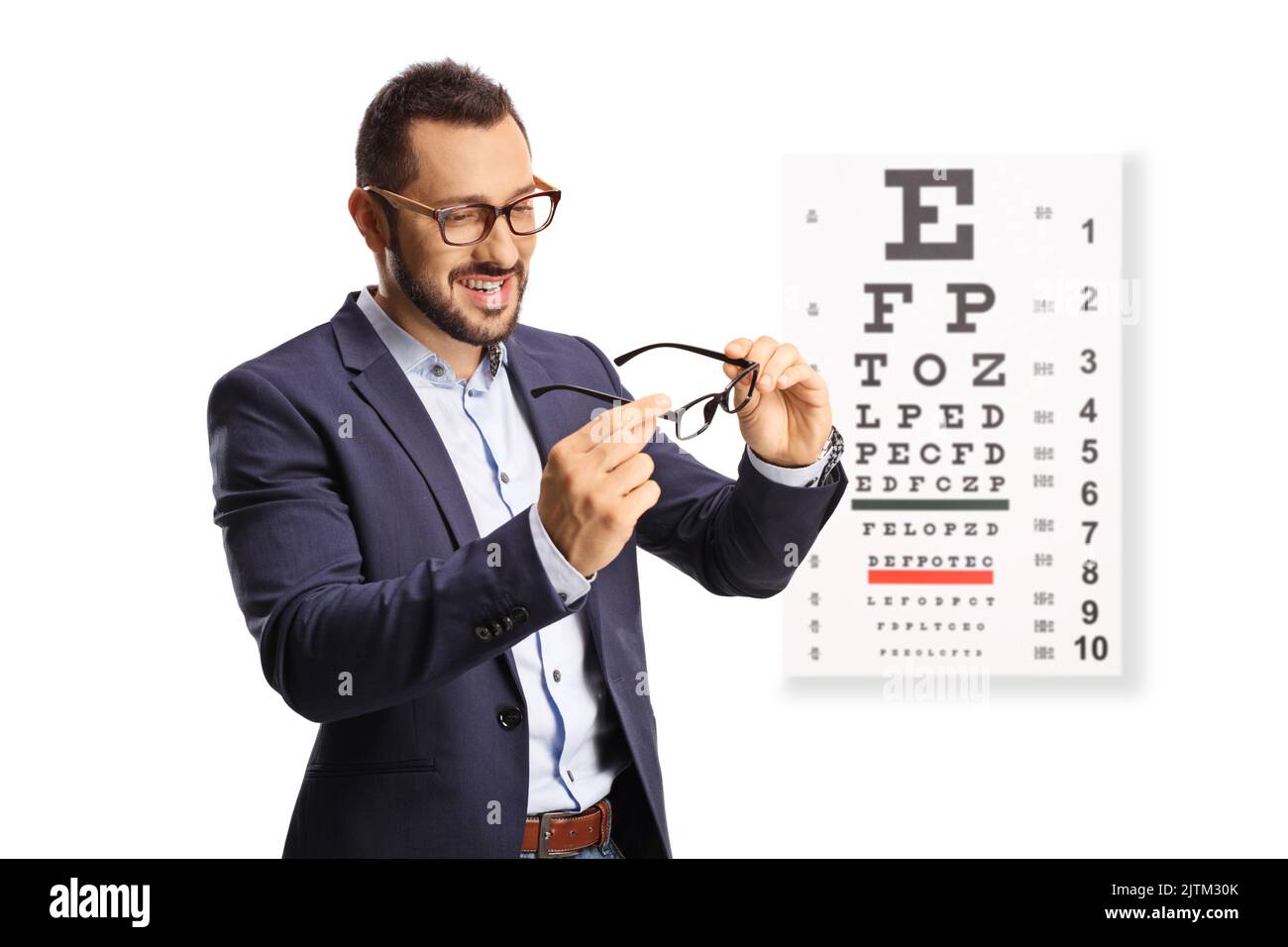 Young man trying pairs of eye glasses in front of an eye exam board