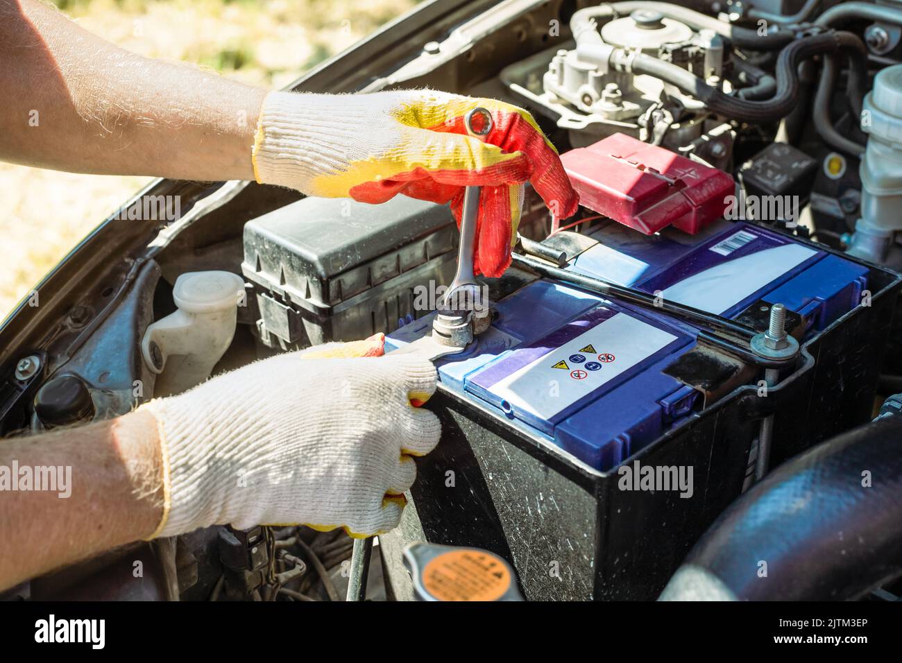Car battery replacement. The car mechanic repairs the car, unscrews the