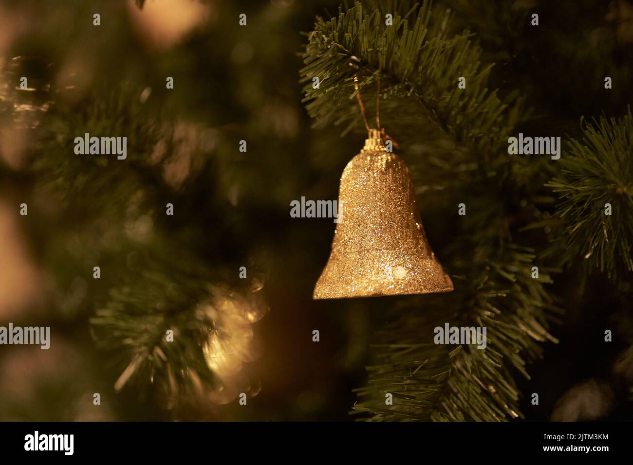 Selective focus. The branch of the Christmas tree is decorated with golden bell toys. The concept of decorating a Christmas tree for the new year. Overlay for your design. High quality photo Stock Photo
