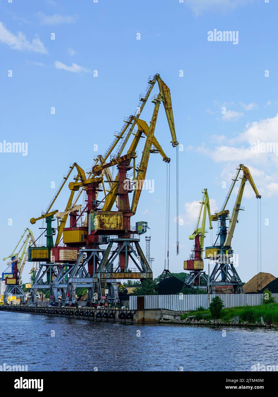 Bulk cargo terminal in port with many shore cranes and piles of coal