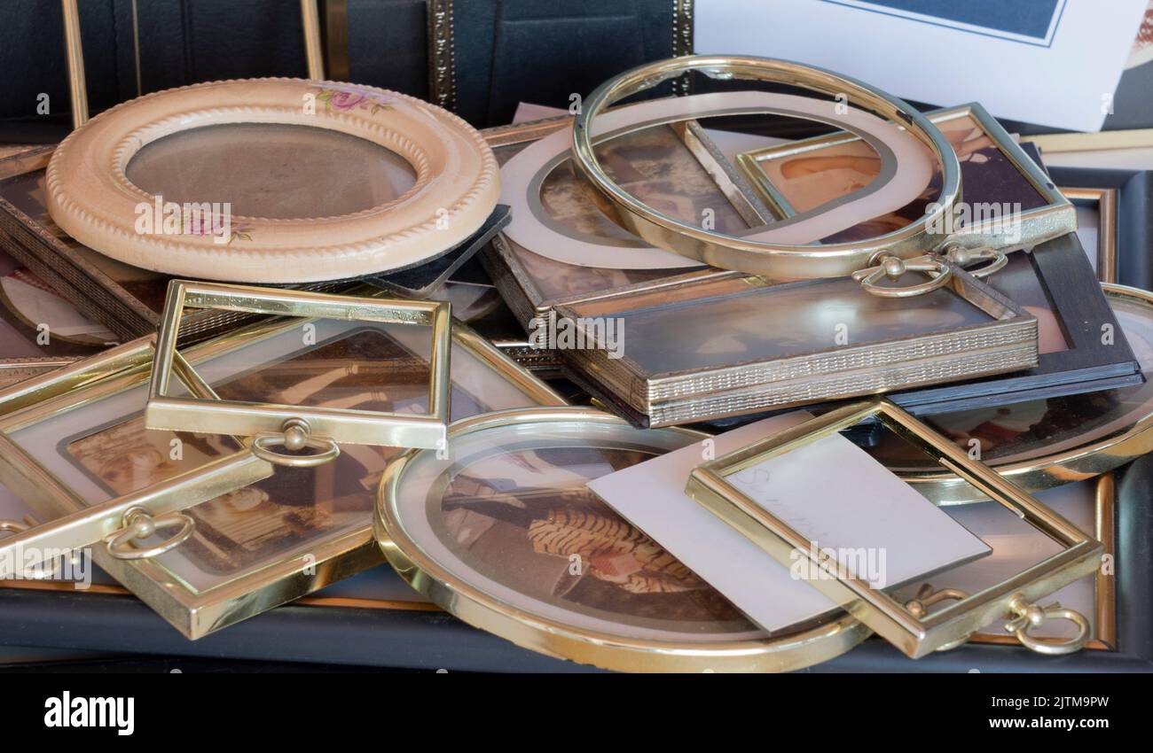 Multiple picture frames to fill with photos. Here is a pile of unused small picture frames including glass, rims, framework, mats, and a few photos. Stock Photo
