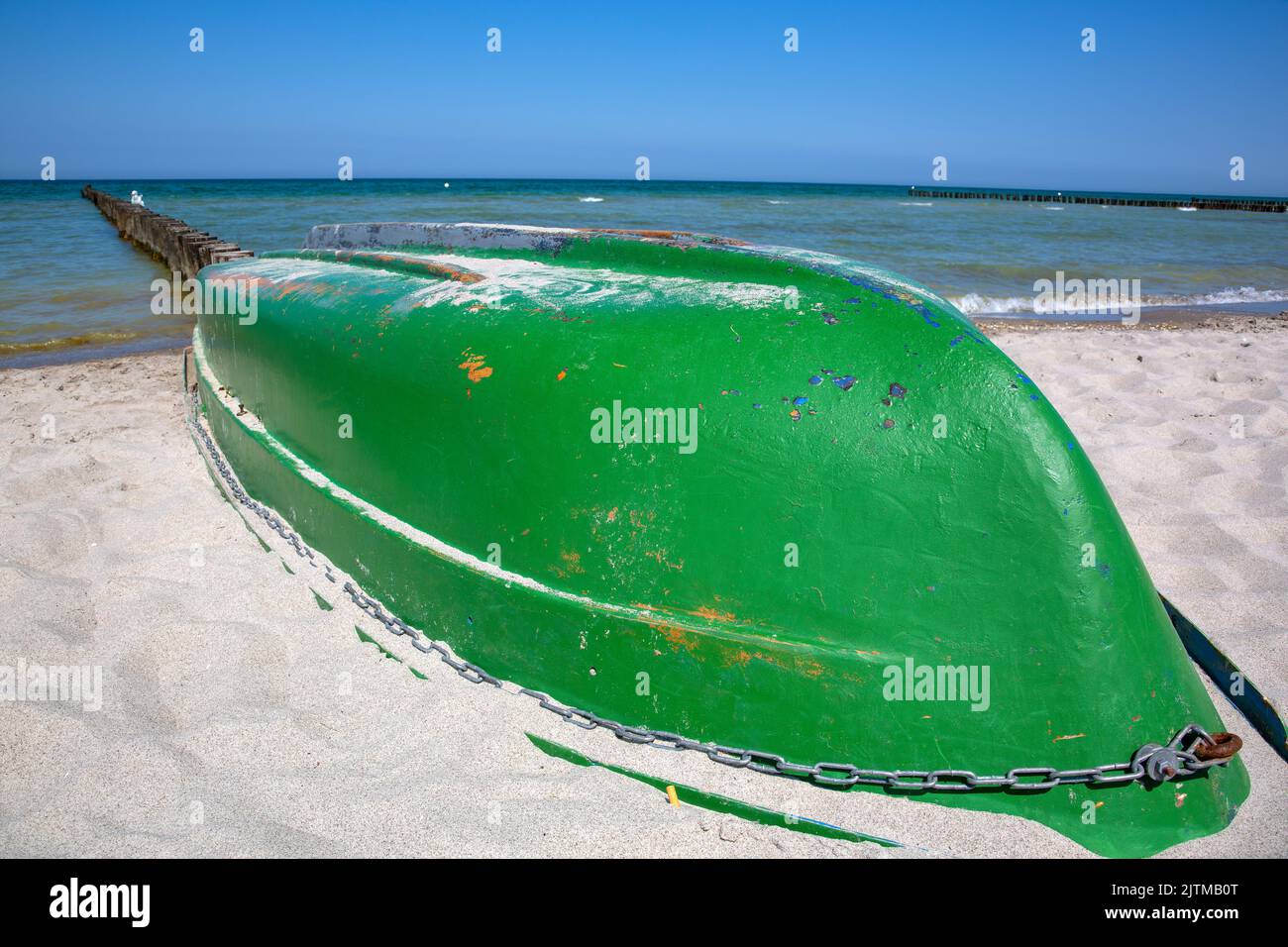 Green fishing boat stranded upside down in the sand of a beach Stock Photo