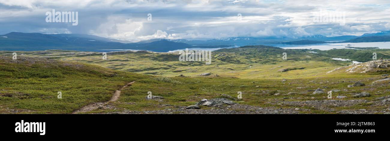 Panoramic landscape with beautiful Virihaure lake, snow capped mountain, birch trees and footpath of padjelantaleden hiking trail. Sweden, Lapland Stock Photo