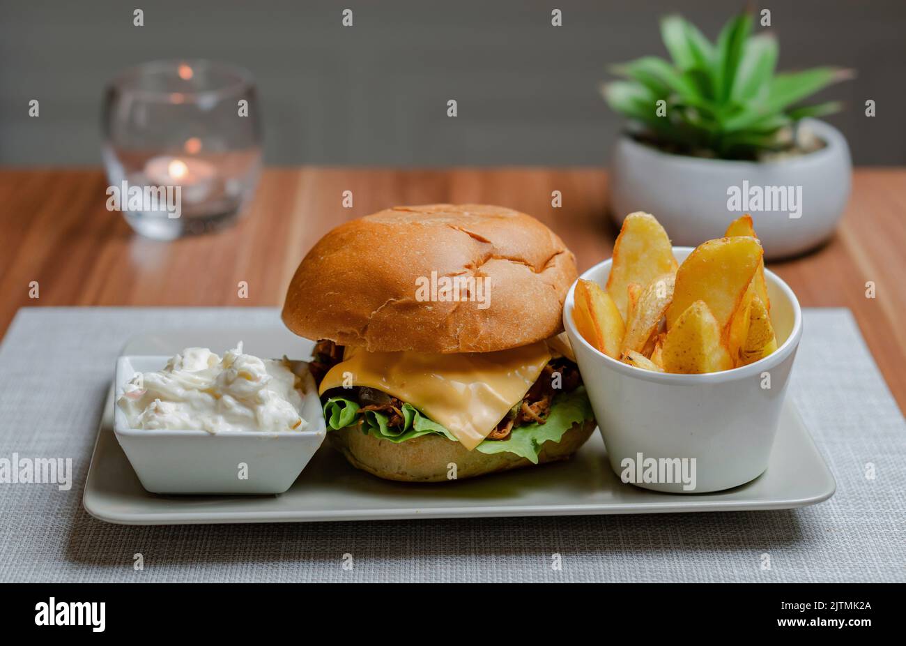 Cheesy Pulled Pork Burger with Chips and Cabbage salad, Hotel background Stock Photo