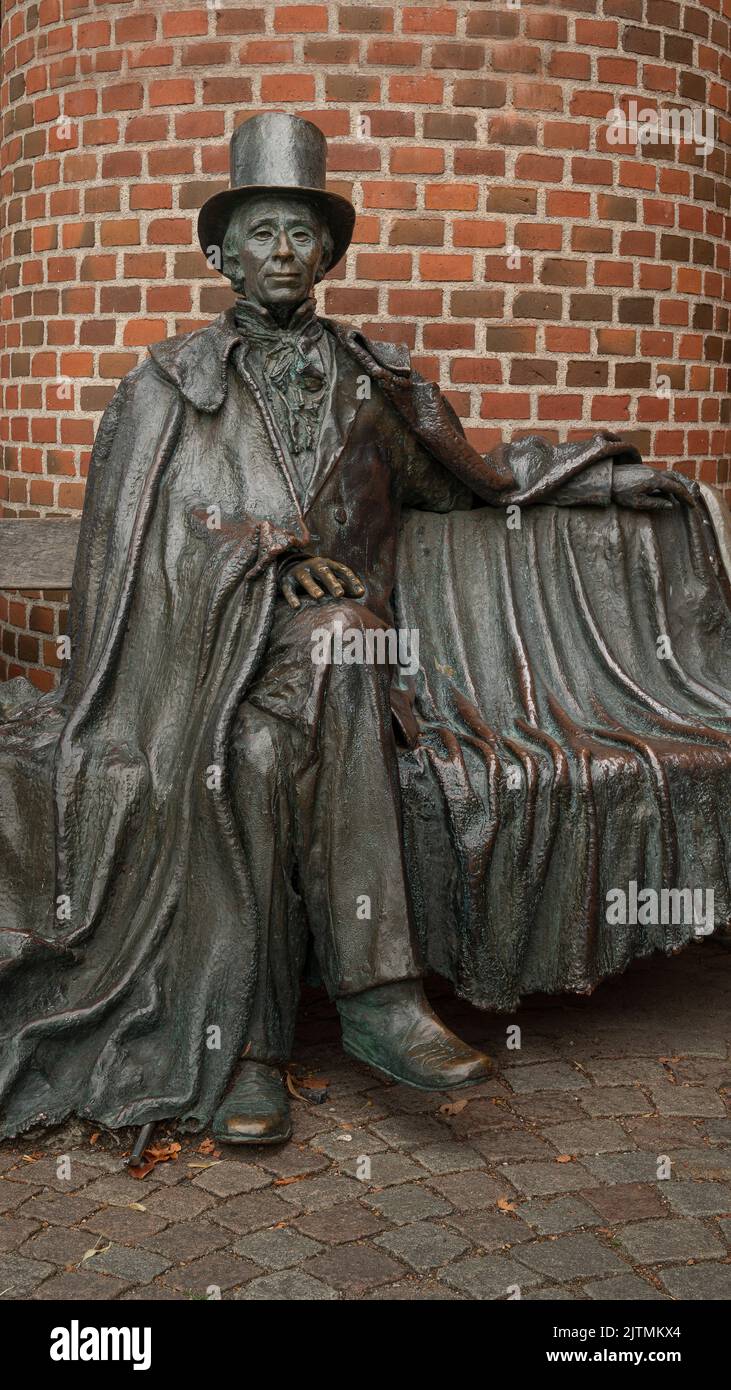 bronse statue of th danish author H C Andersen sitting on a bench in front of a red brickwall, Odense, Denmark, August 28, 2022 Stock Photo