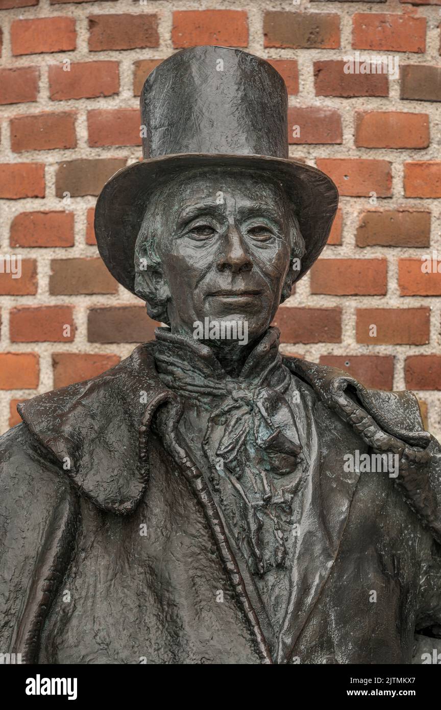 bronse statue of th danish author H C Andersen in a top hat in front of a red brickwall, Odense, Denmark, August 28, 2022 Stock Photo