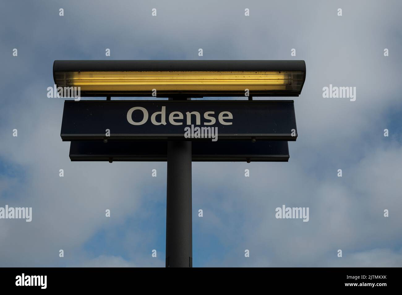 Signpost with a yellow lamp against the blue sky at the railway station in Odense, Denmark, August 28, 2022 Stock Photo