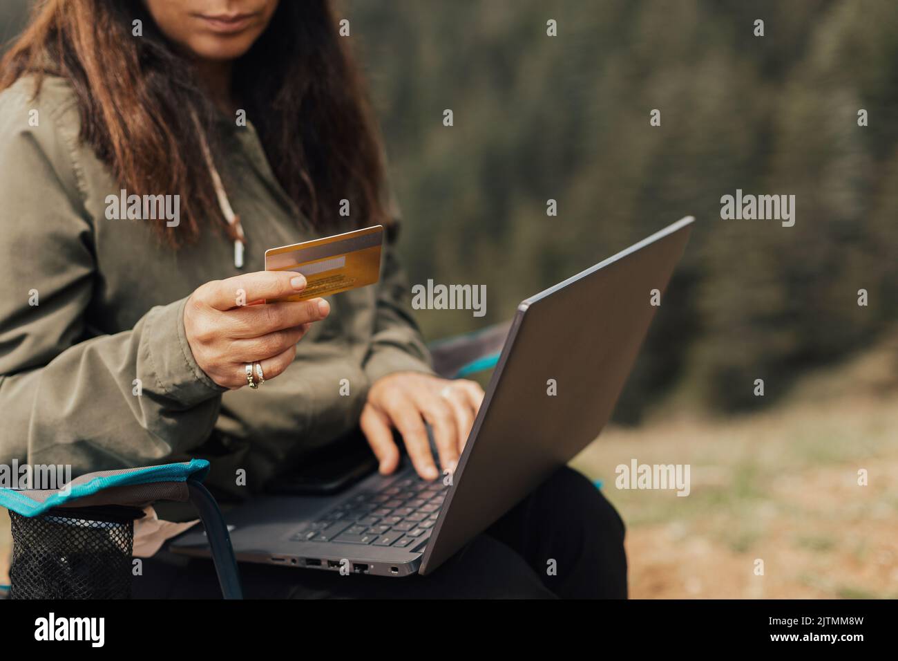 Woman working with her computer in nature, working with a computer in the forest. Stock Photo