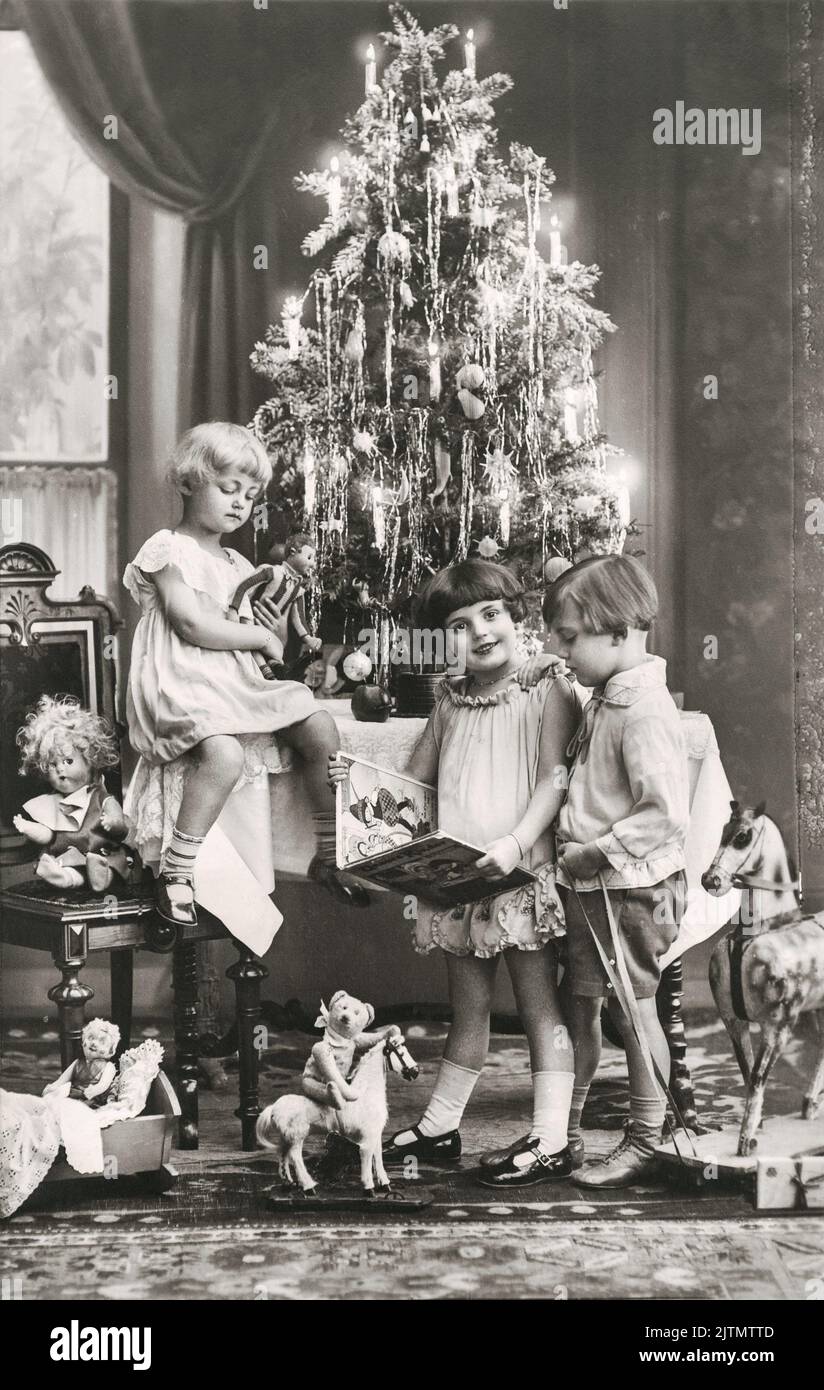 Antique photo of happy kids with christmas tree, gifts and vintage toys Stock Photo