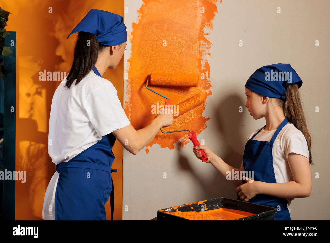 Cheerful family having fun with paint, using roller paintbrush and