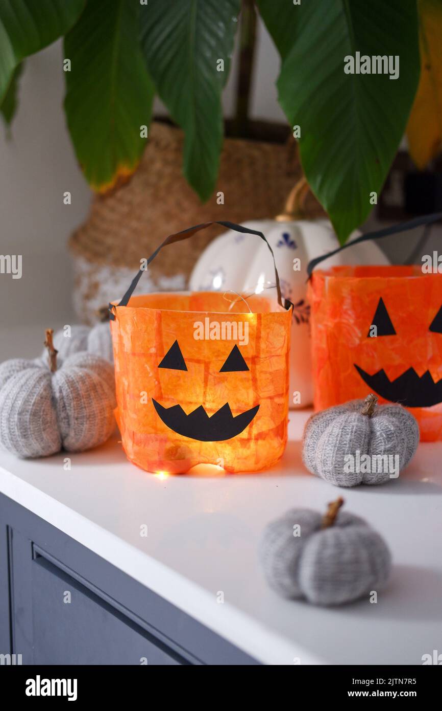 Recycled milk bottles turned into fun pumpkin lanterns for Halloween using orange tissue paper, glue and black card Stock Photo