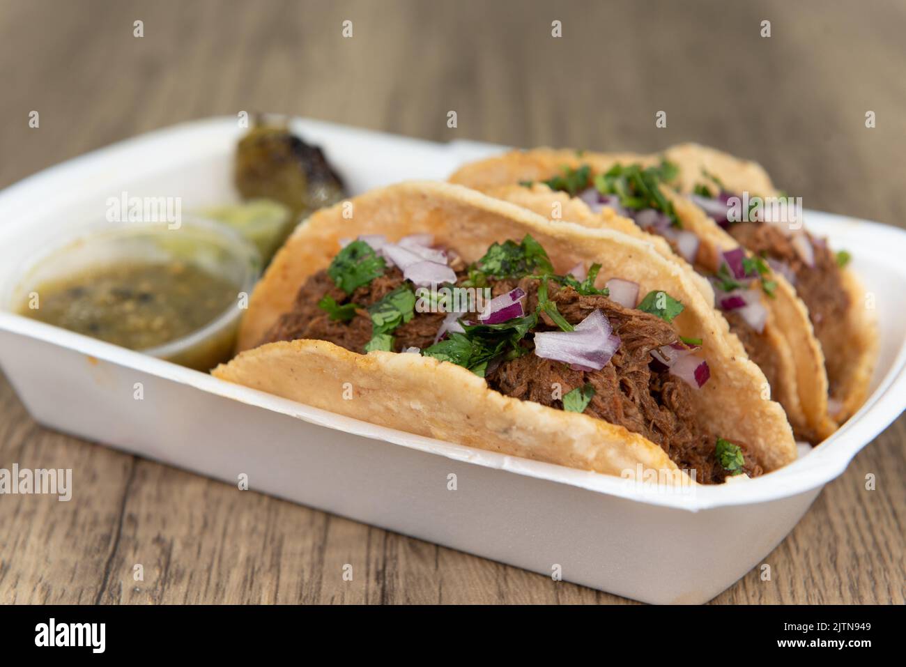 Loaded slow cooked birria meat tacos topped with onions and served with