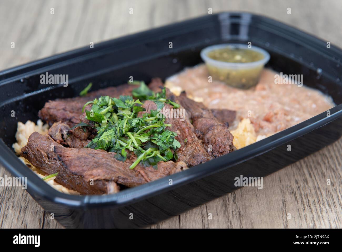 Take out order of ranchera with rice and beans is conveniently packed in a microwavable container. Stock Photo