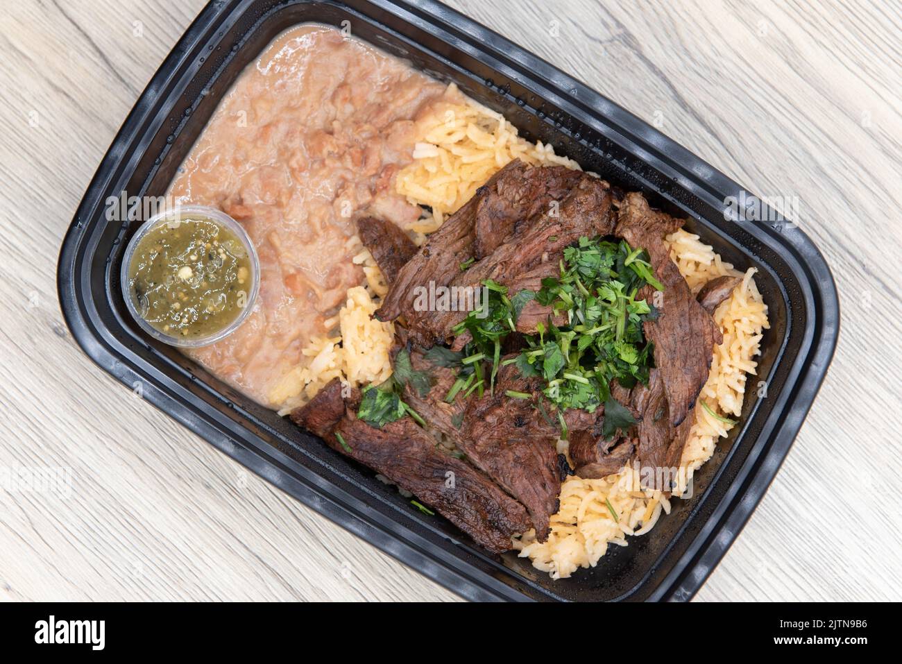 Overhead view of take out order of ranchera with rice and beans is conveniently packed in a microwavable container. Stock Photo