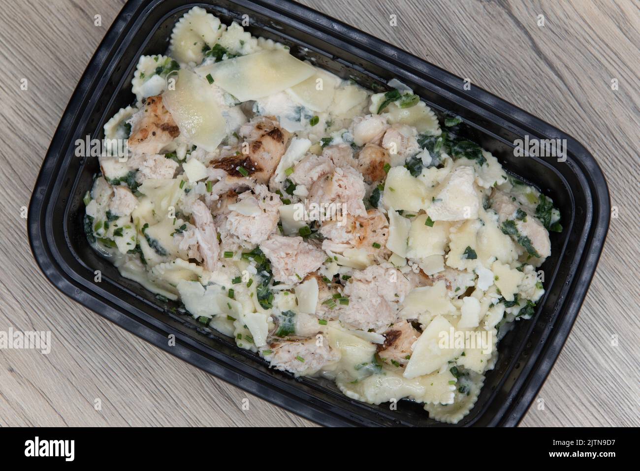 Overhead view of take out order of chicken with bow tie pasta is conveniently packed in a microwavable container. Stock Photo