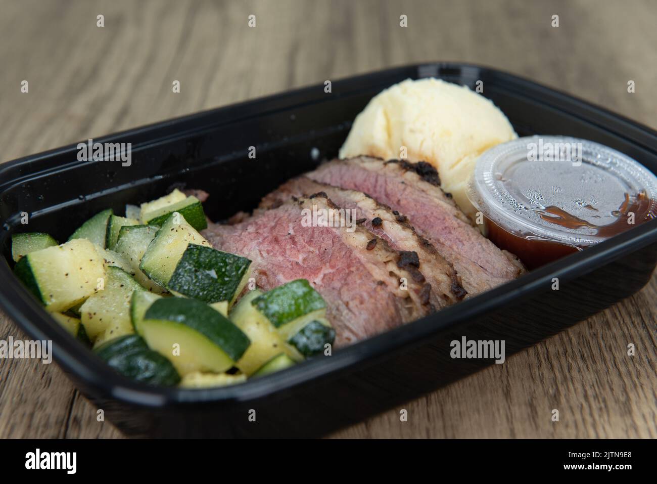 Take out order of Tri tip steak with mashed potatoes is conveniently packed in a microwavable container. Stock Photo