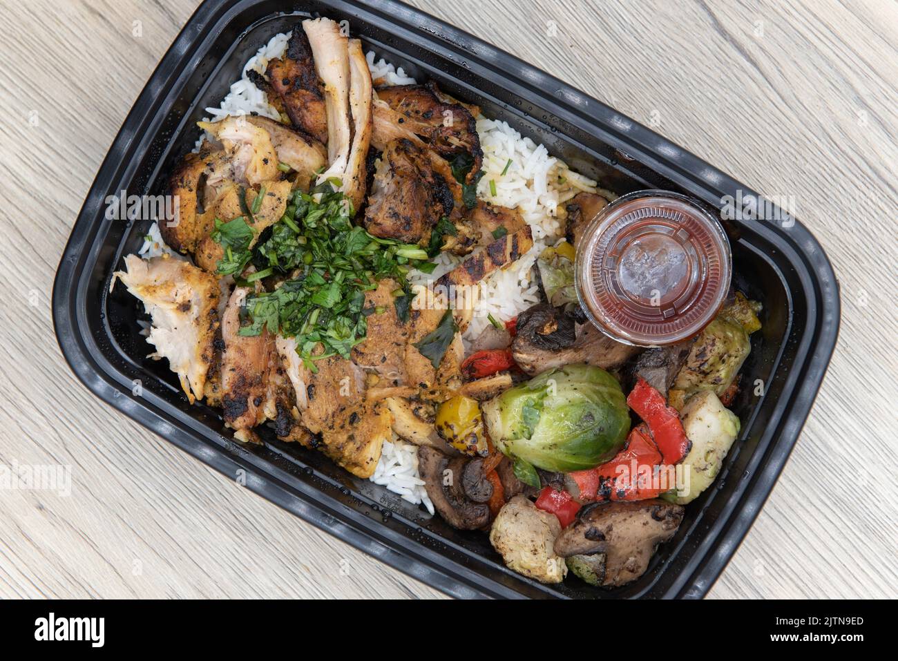 Overhead view of take out order of shawarma chicken with jasmin rice is conveniently packed in a microwavable container. Stock Photo