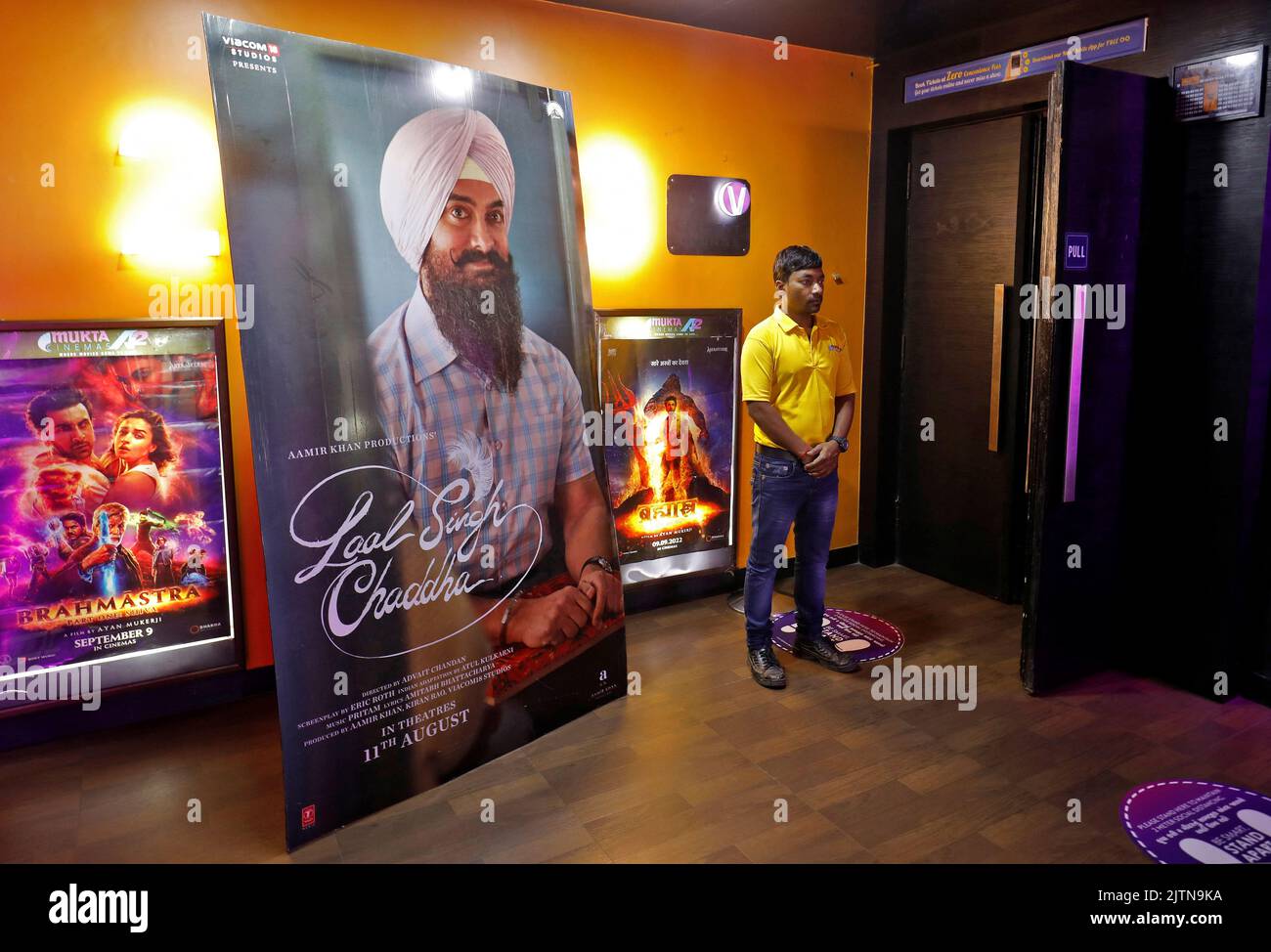 A ticket checker waits for film-goers at the gate of a cinema hall showcasing Aamir Khan-starrer 'Laal Singh Chaddha', an official remake of the 1994 film 'Forrest Gump' in Ahmedabad, India, August 26, 2022. REUTERS/Amit Dave Stock Photo