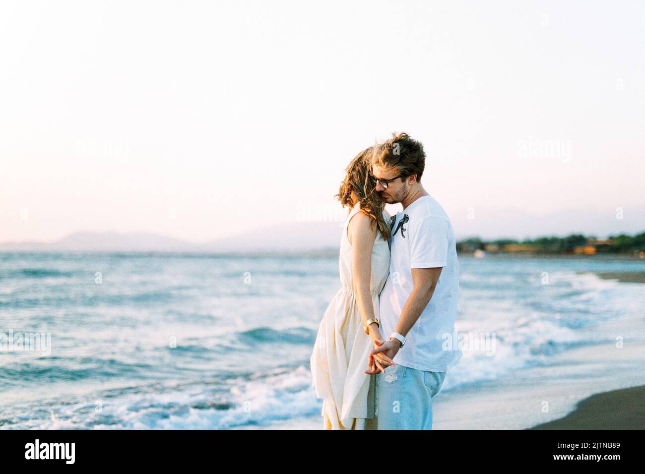 Man and woman hugging holding hands on the beach Stock Photo - Alamy
