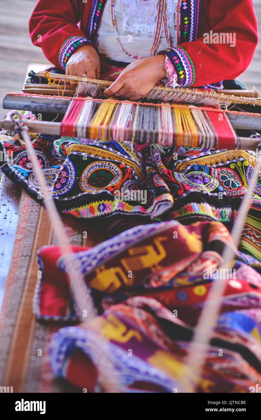 Indigenous woman showing traditional weaving technique and textile making in the Andes mountain