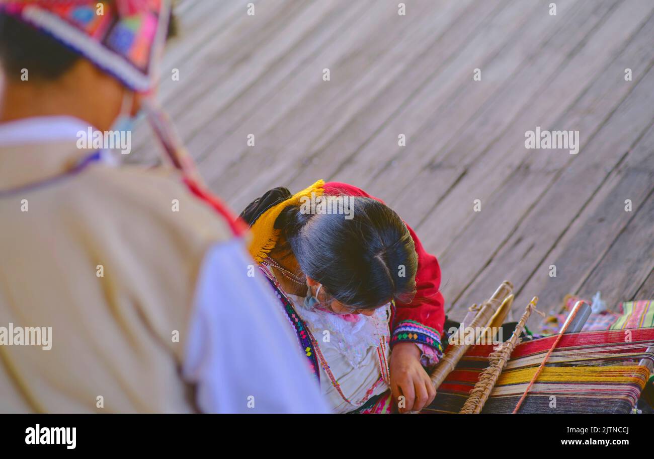 Indigenous woman showing traditional weaving technique and textile making in the Andes mountain