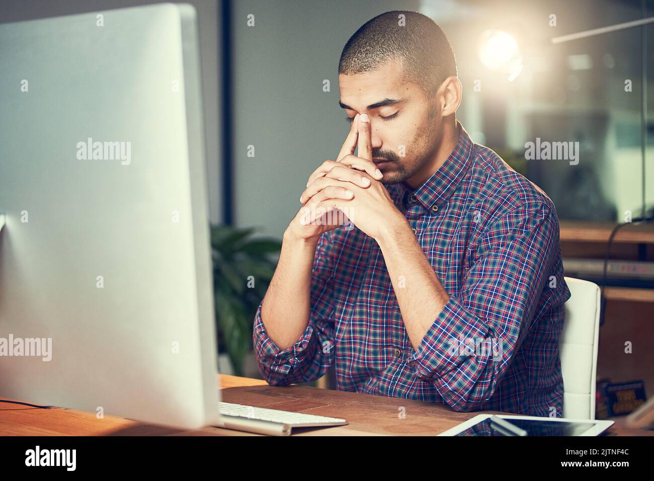 On the verge of sinking under all the stress. a stressed out designer working late in an office. Stock Photo