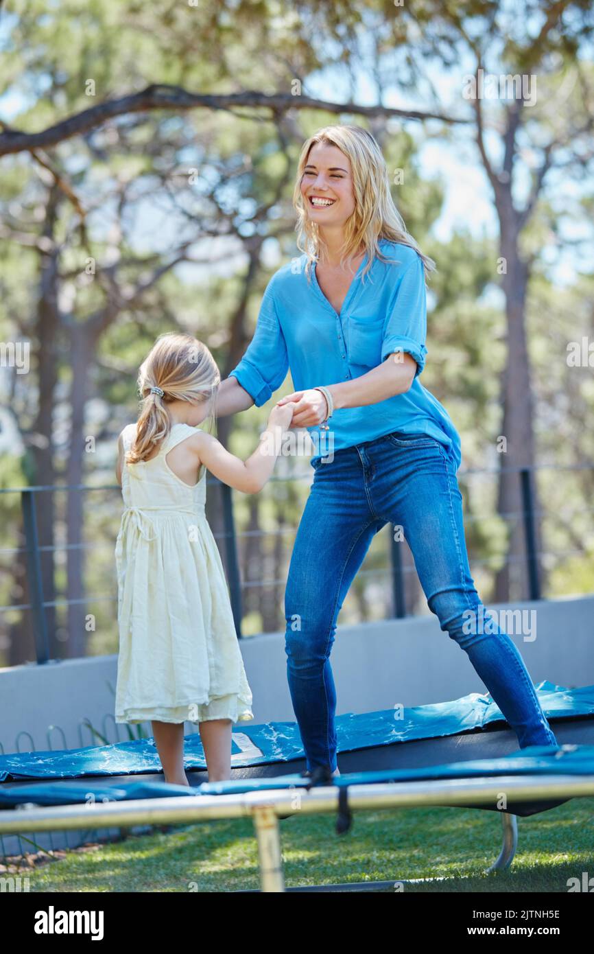 Jump around. a young mother playing on the trampoline with her daughter outside. Stock Photo
