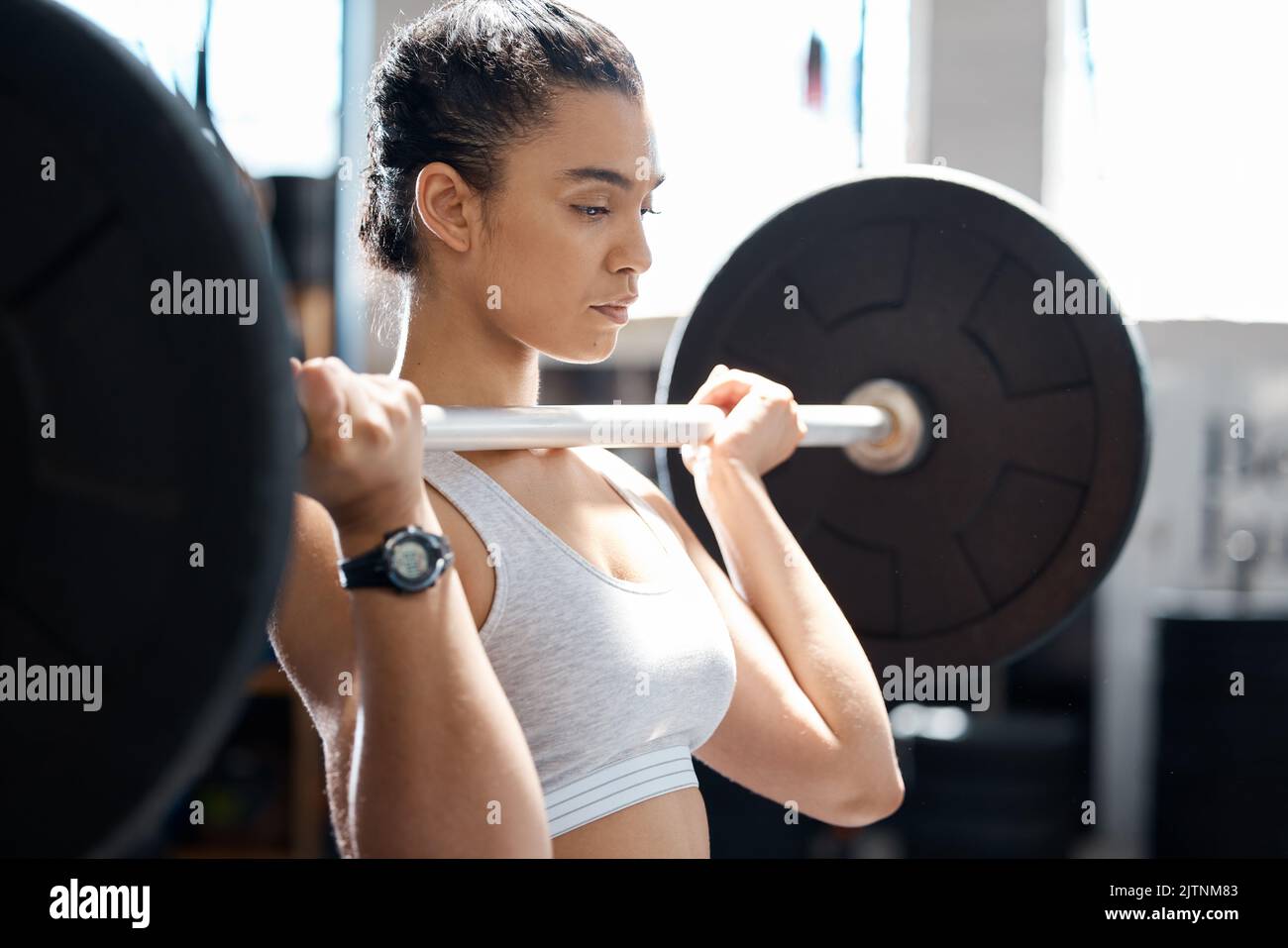 Woman fitness, motivation and barbell workout in wellness gym for