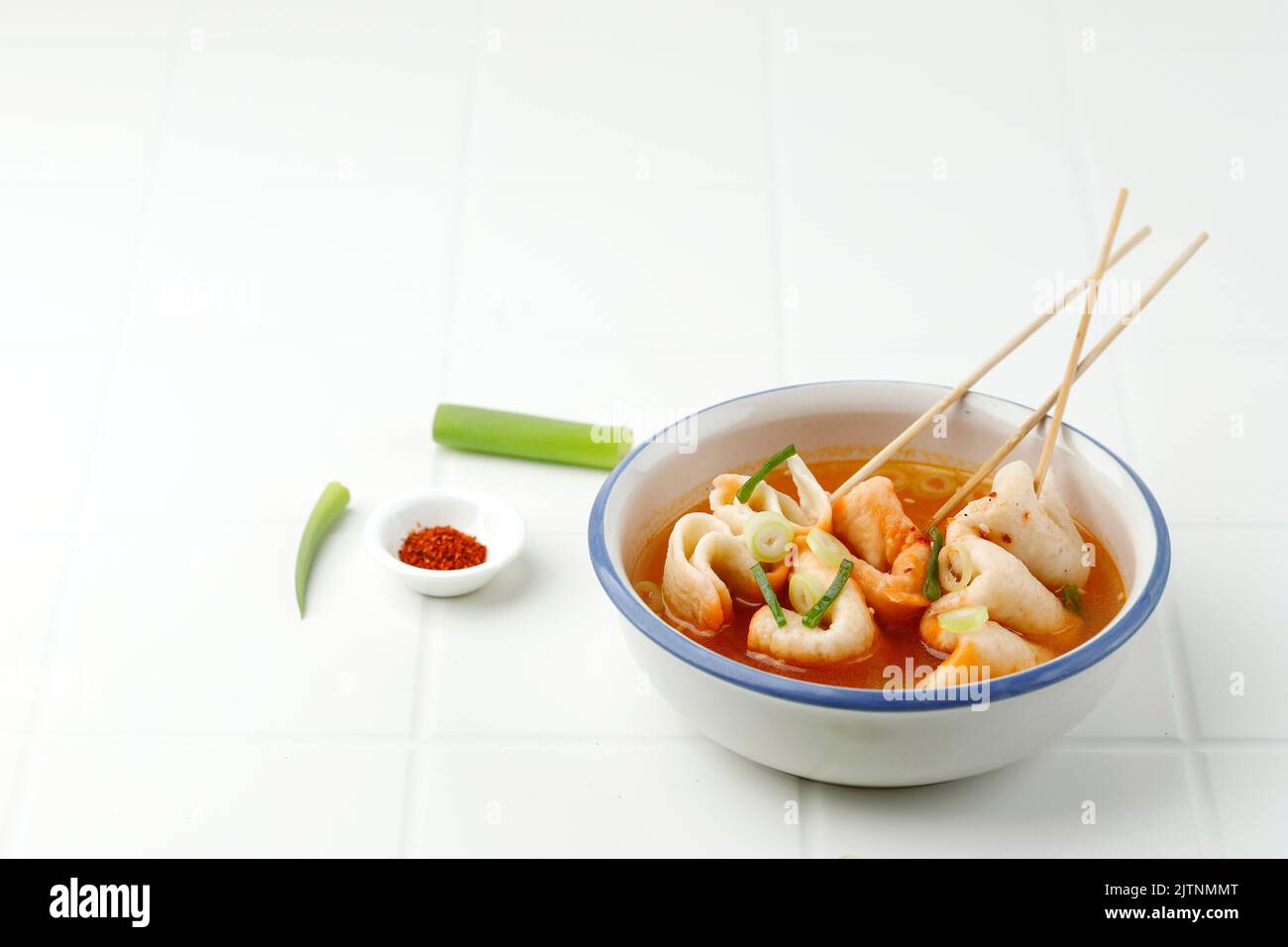 Spicy Eomukguk or Odeng Soup, Korean Popular Street Food Made from Fish Cake Eomuk and Spicy Gochujang Paste. On White Table, COpy SPace for Text Stock Photo