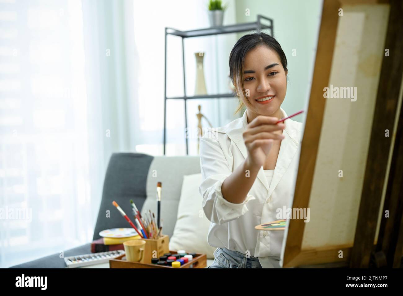Charming young Asian female painter painting her creative artwork on ...