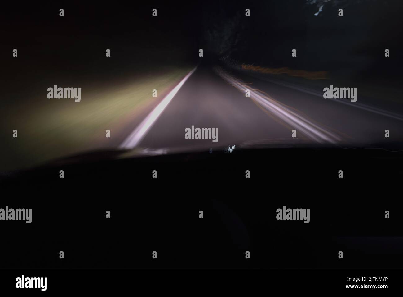 Blurred motion driving at night on a dark road illuminated only by