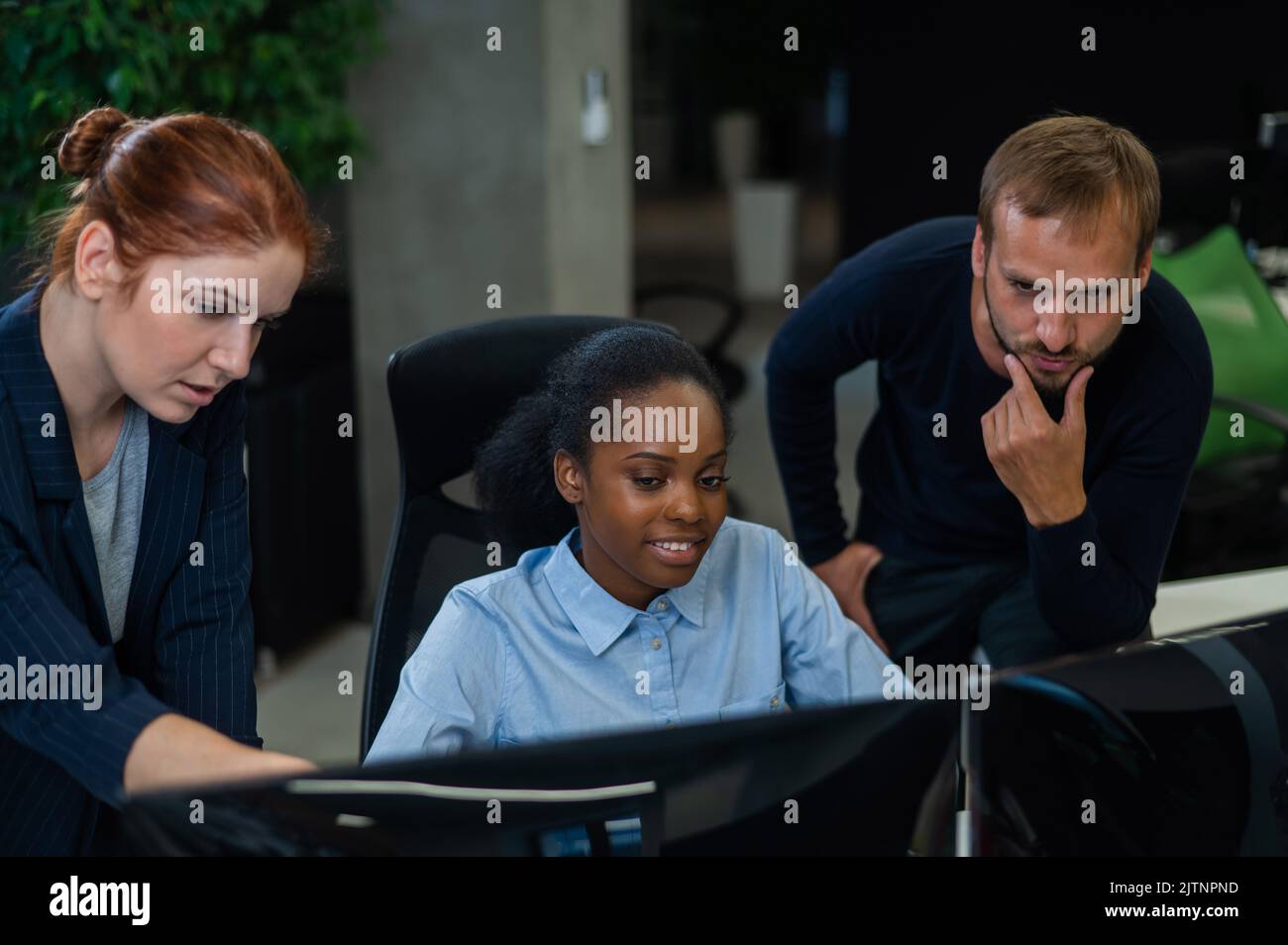 Colleagues discuss work. African young woman, caucasian and red-haired ...