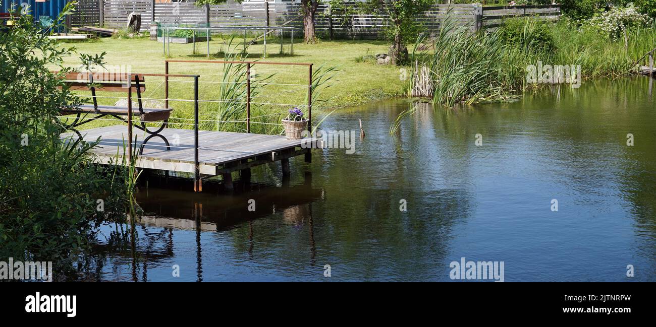 Handmade  pond and wooden pier in  poor Lithuanian   village Stock Photo