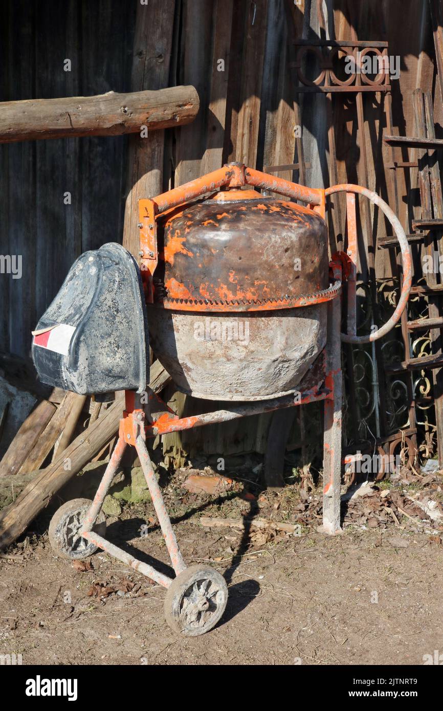 Small old concrete mixer near the wooden  shed Stock Photo