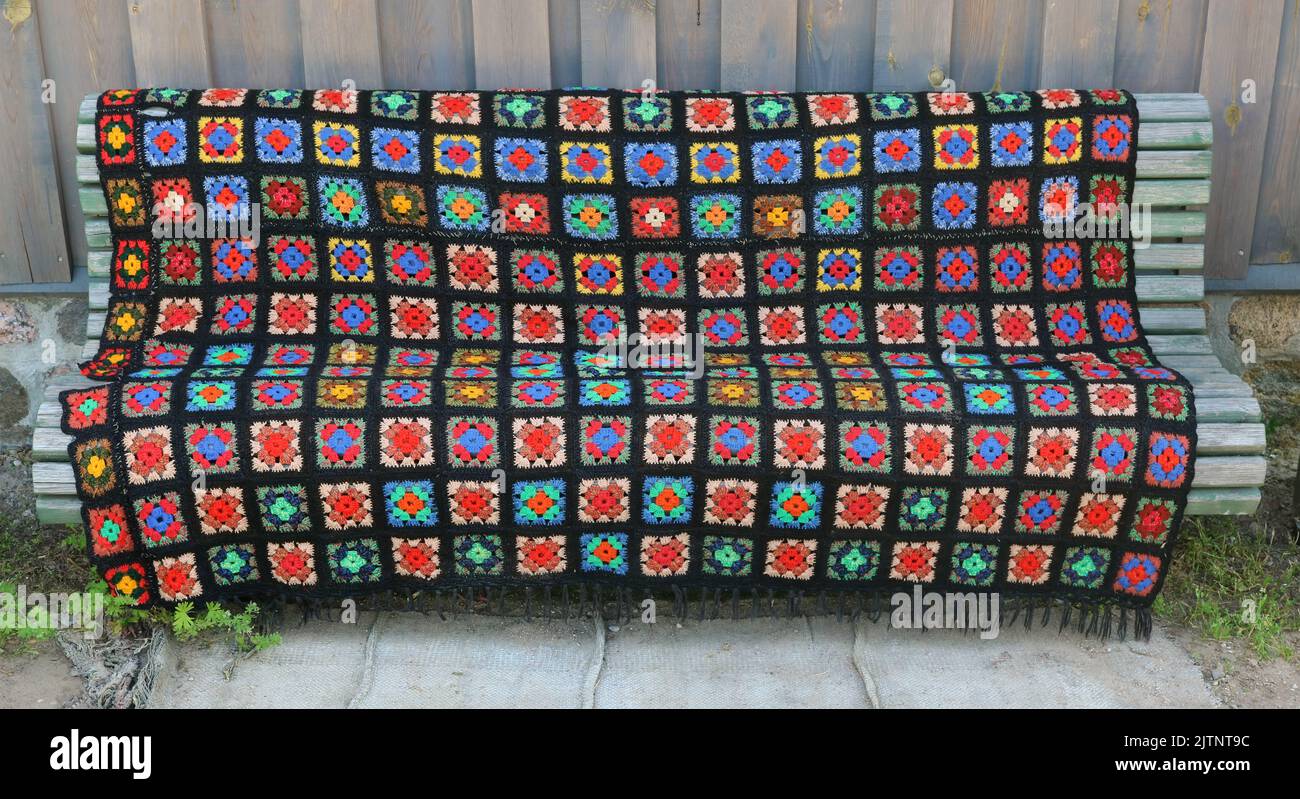Homemade knitted old bedspread on a wooden  bench Stock Photo