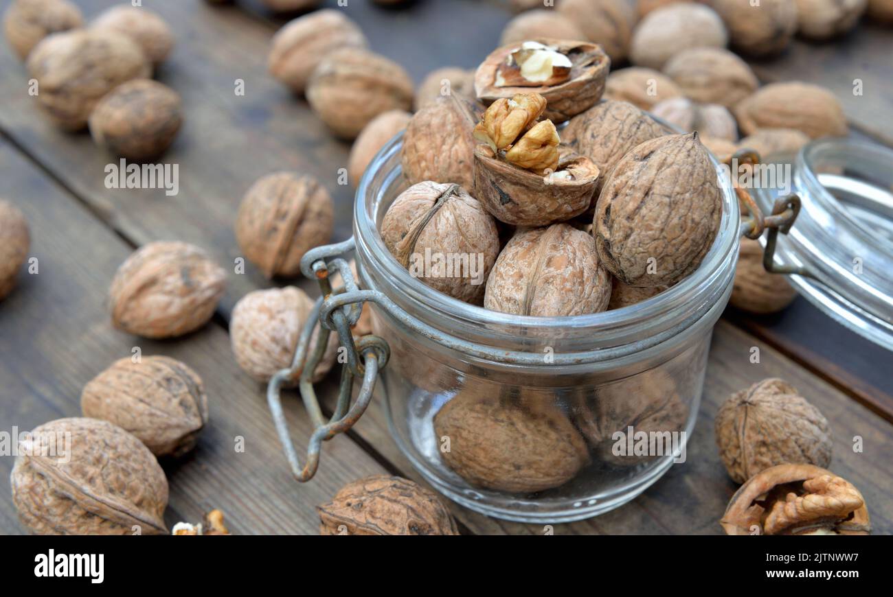 closeup on walnuts in a glass jar among others on wooden table Stock Photo