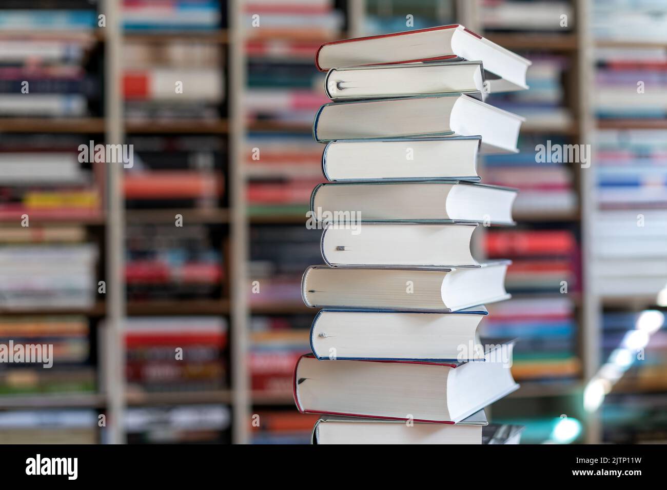 a stack of novels in front of a wall of books Stock Photo