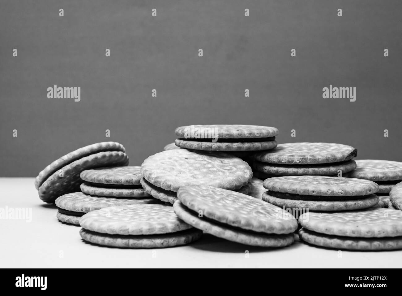 A grayscale closeup shot of a pile of delicious fresh chocolate and cocoa cookies on a table Stock Photo