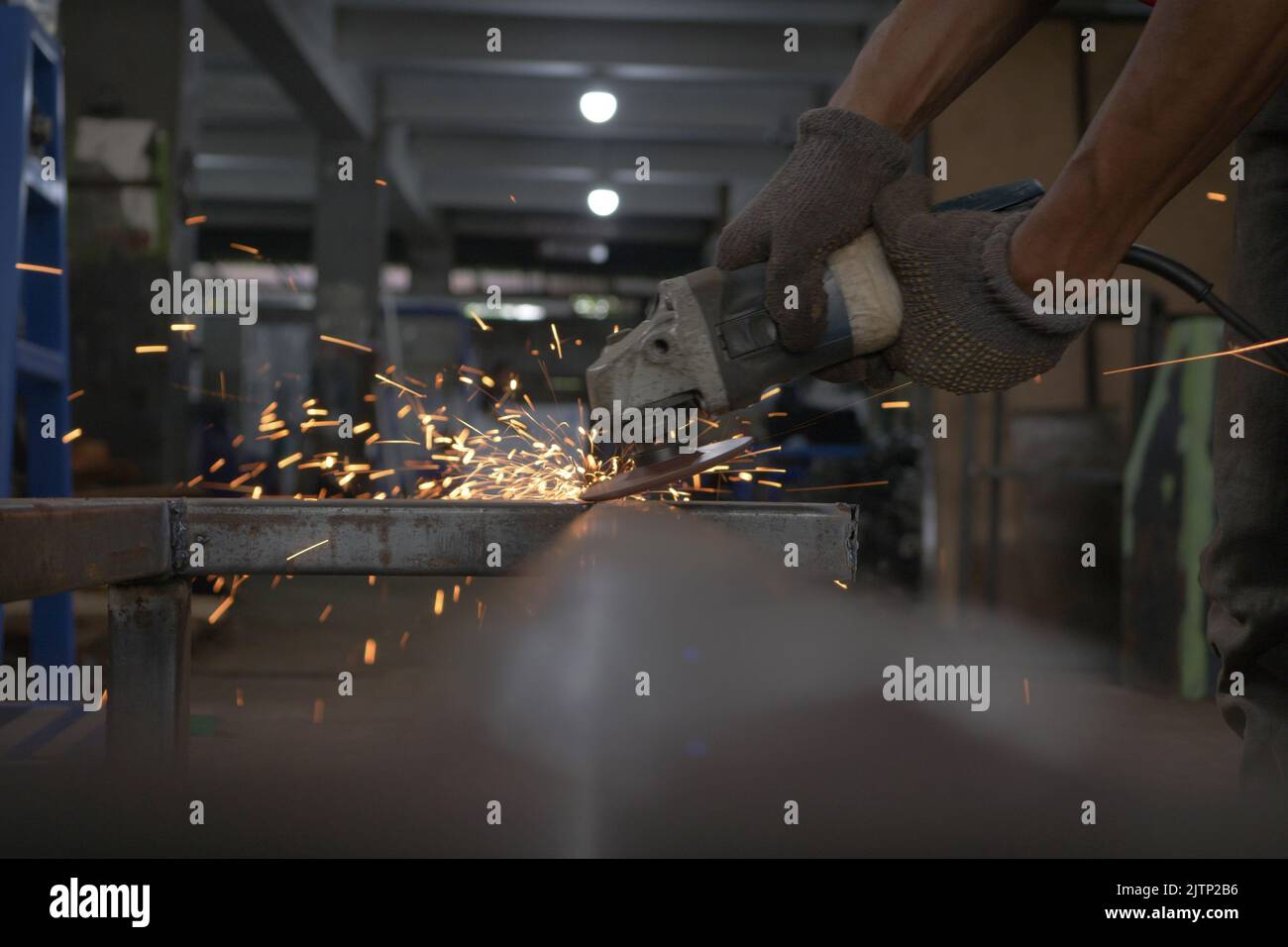 Worker grinding metal with grinding machine. Sparks when grinding iron