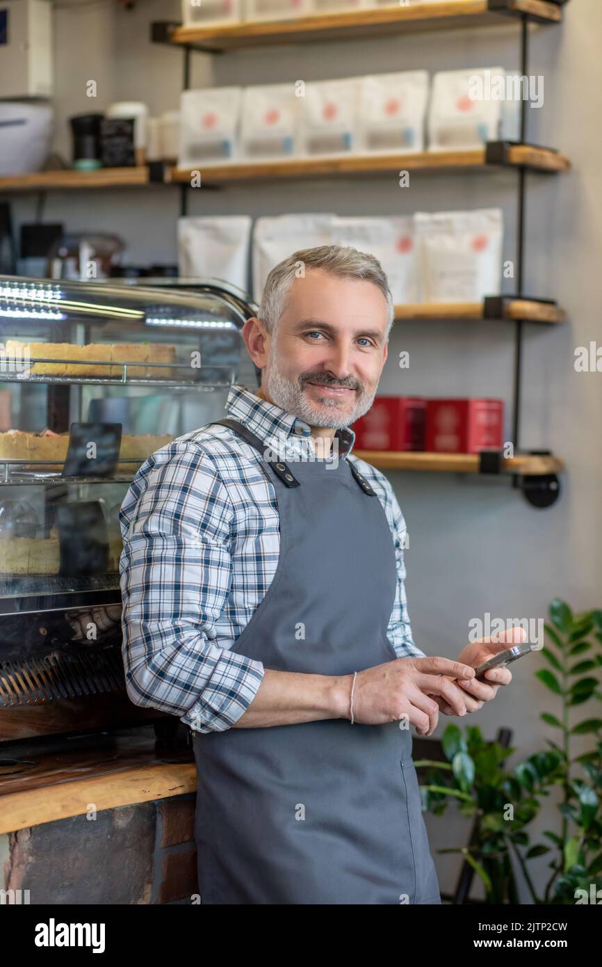 Joyous cafe employee in the apron posing for the camera Stock Photo - Alamy