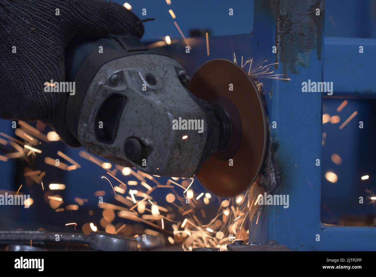 Worker grinding metal with grinding machine. Sparks when grinding iron