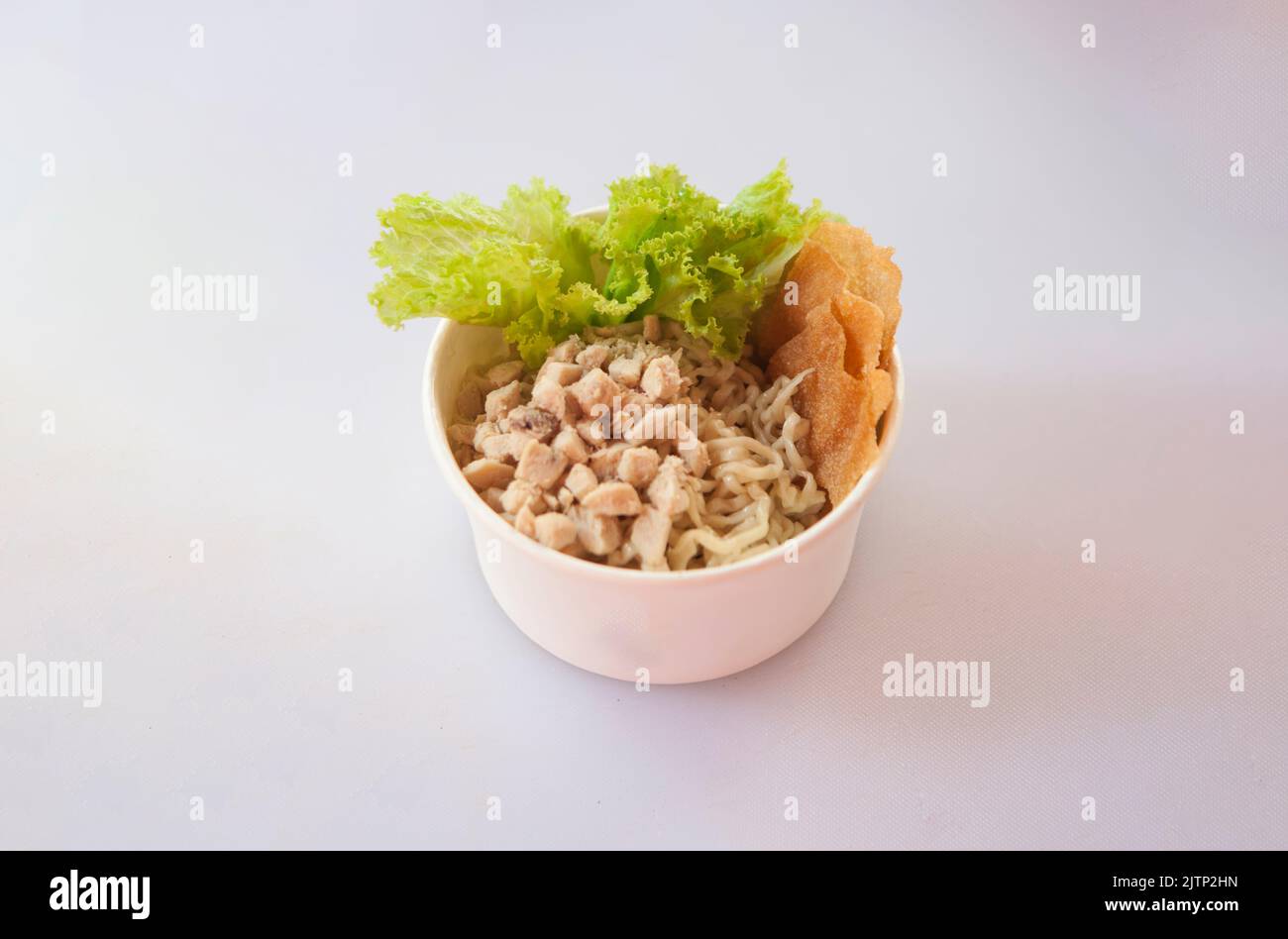 Mie Ayam or  chicken noodle on white background. Yellow wheat noodles with chicken meat topping, Served with fried dumplings, Stock Photo