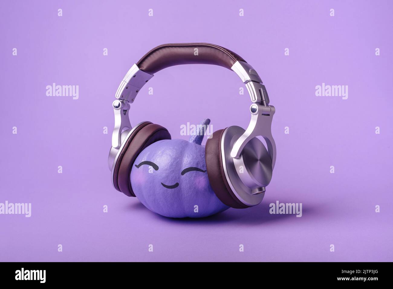 Happy Halloween Funny cheerful purple pumpkin with headphones on a purple background. Creative backdrop concept for Halloween holiday and party. Kids Stock Photo