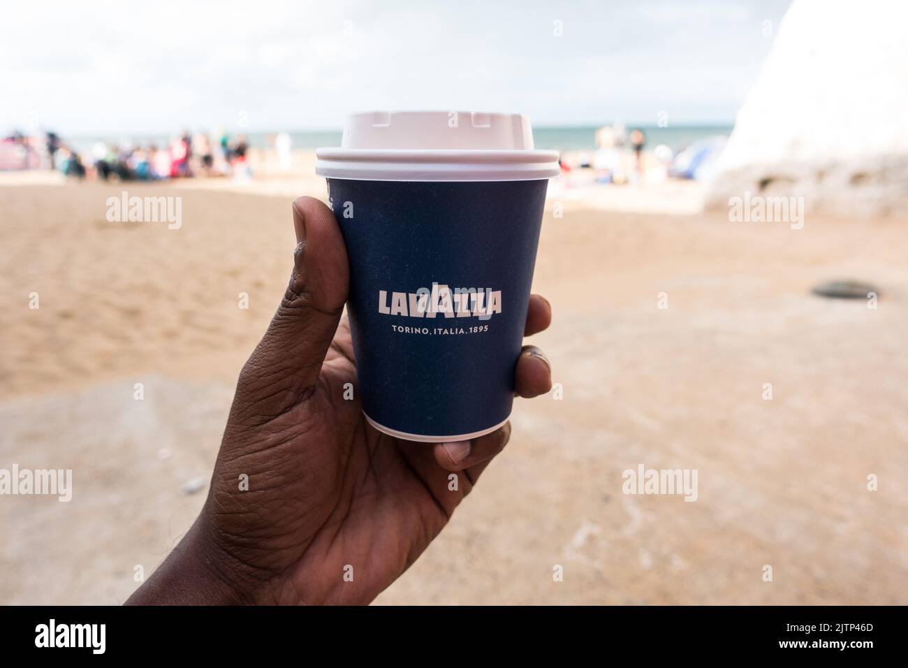 LavAzza take away coffee cup in adult males hand at a beach shore Stock Photo