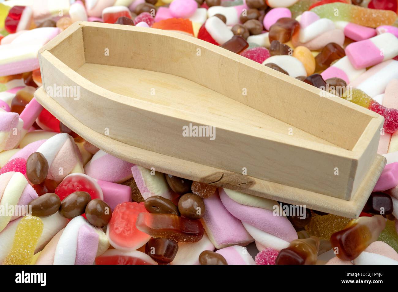 Wood coffin on top of pile of assorted sweets, junk food and candy concept for death caused by diabetes and metabolic disease, obesity due to an unhea Stock Photo