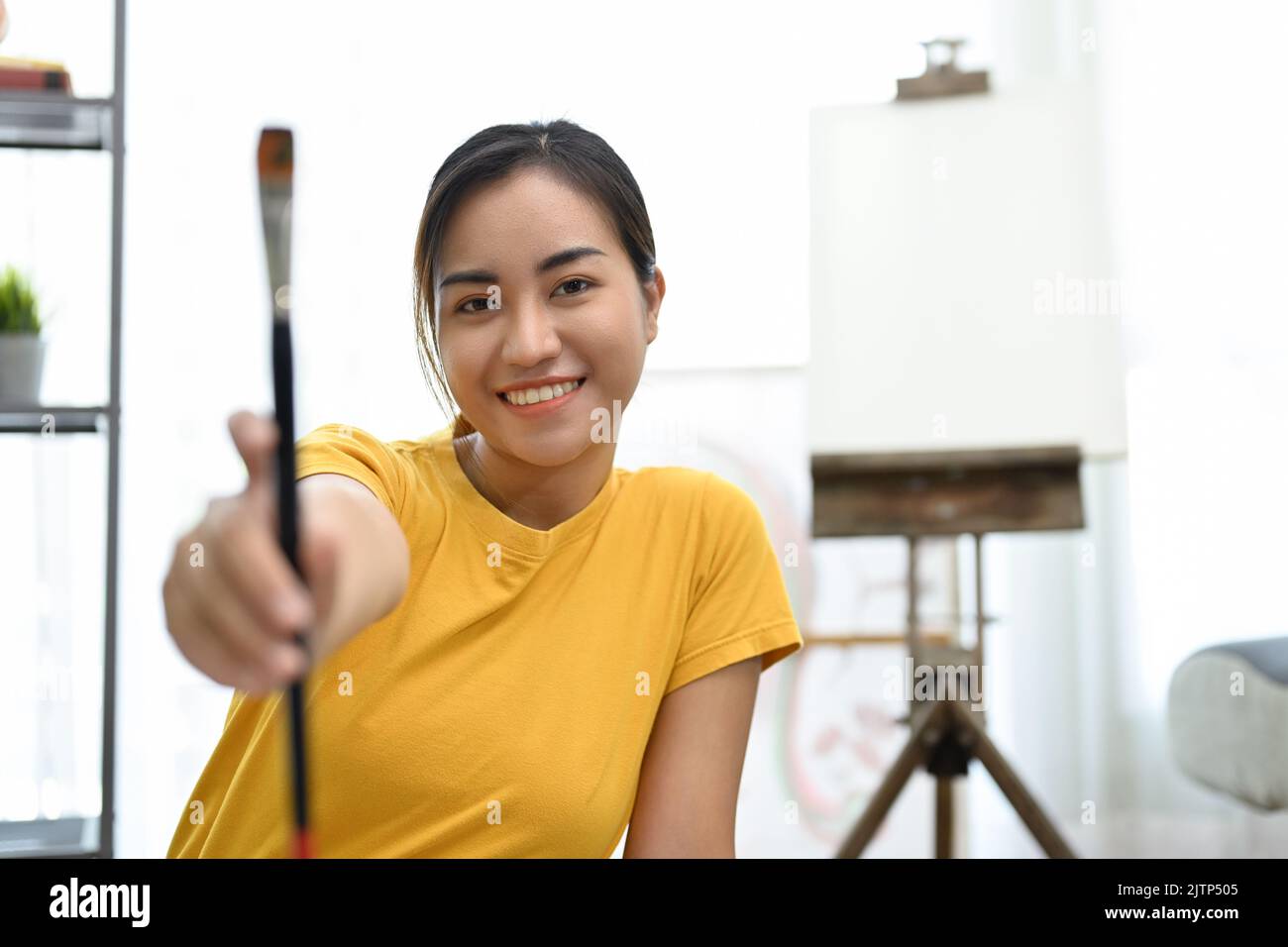 Attractive and beautiful young Asian female painter or artist holding a ...