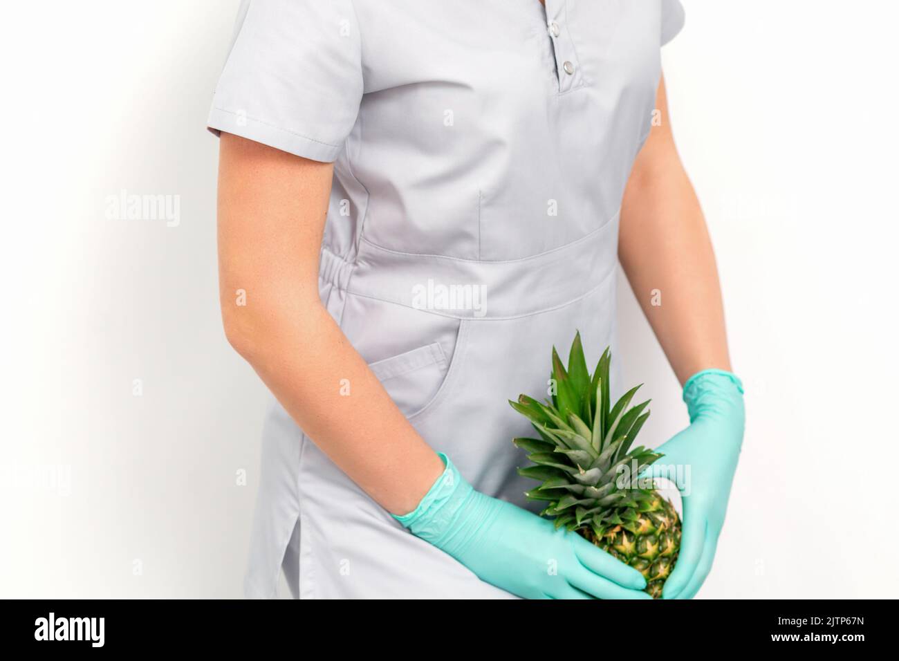 Female doctor beautician with pineapple. Concept of epilation or